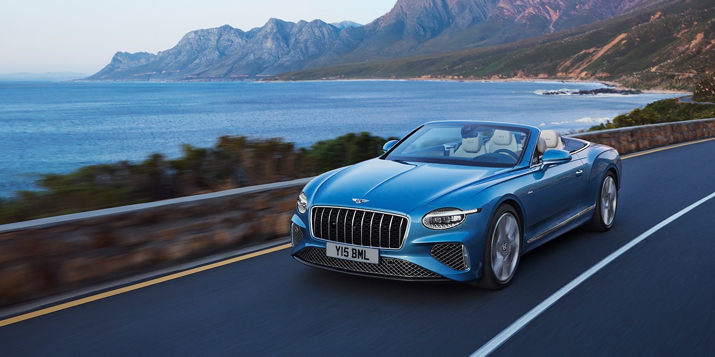 Bentley Hamburg New Bentley Continental GTC Azure convertible in Light Windsor blue paint with 22 inch Azure wheels and chrome grill, driving dynamically by the sea