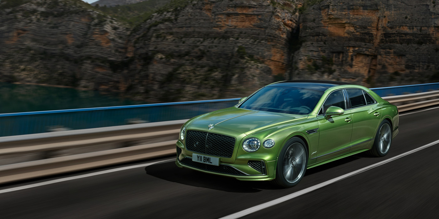 Bentley Hamburg Bentley New Flying Spur Speed v8 hybrid sedan driving dynamically on a mountain road in Tourmaline Green paint