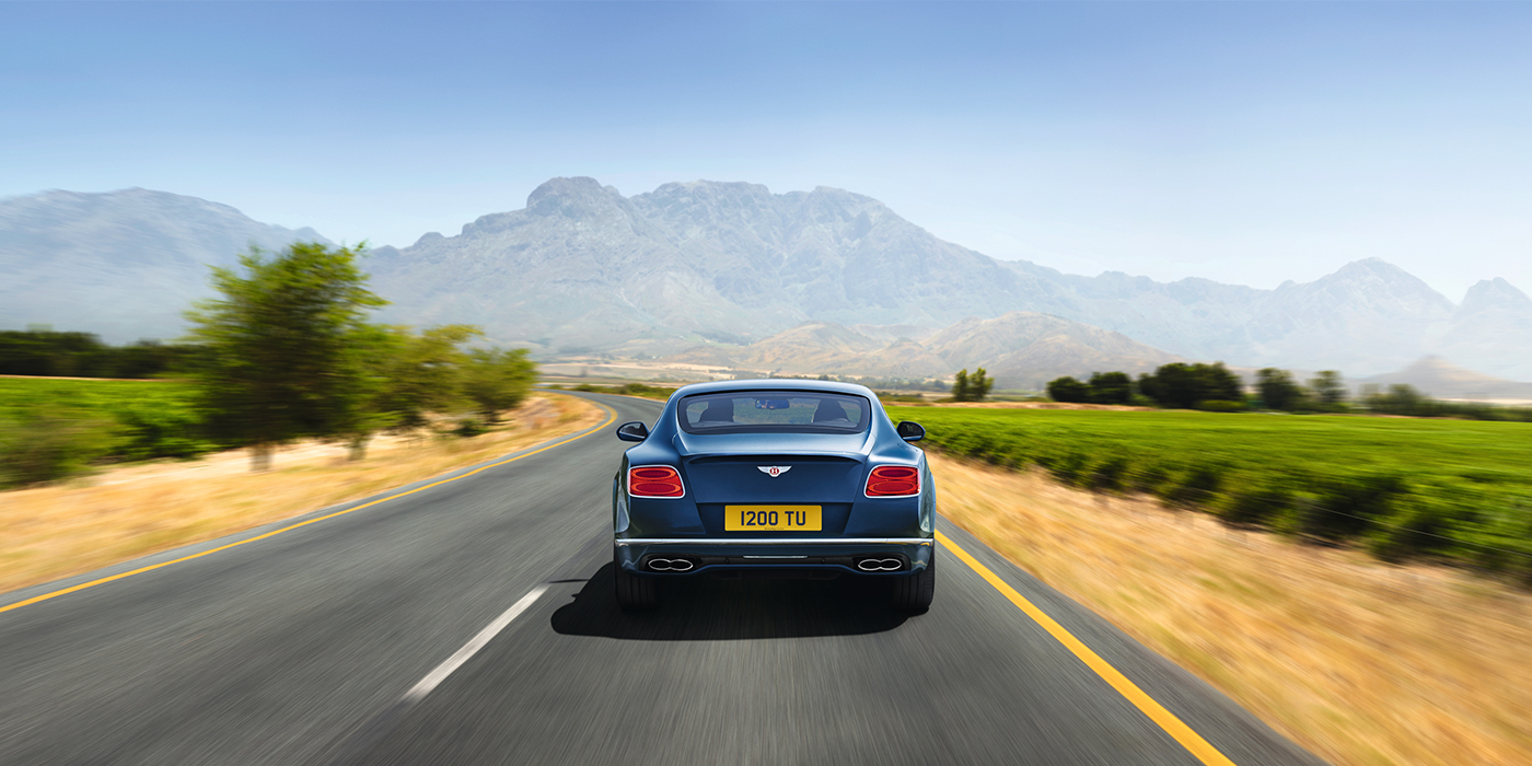 Bentley Hamburg Bentley Pre Owned Bentley Continental GT in Marlin blue paint seen from rear on country road