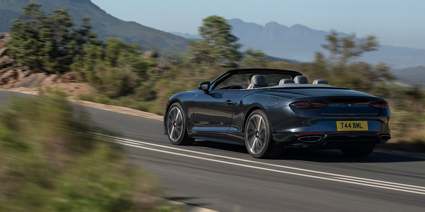 Bentley Hamburg Bentley Continental GTC S convertible in Thunder blue paint rear 3/4 driving on mountain road