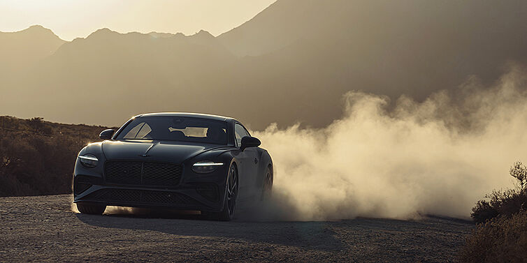Bentley Hamburg Bentley Continental GT coupe in Thunder paint front 3/4 driving with dust trail at sunset