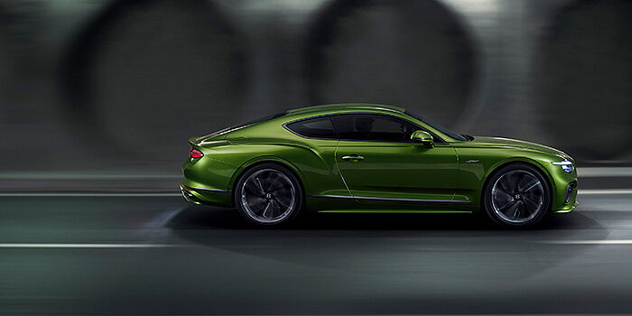  Bentley Hamburg Bentley Continental GT coupe in Tourmaline Green paint driving in profile on a dark road