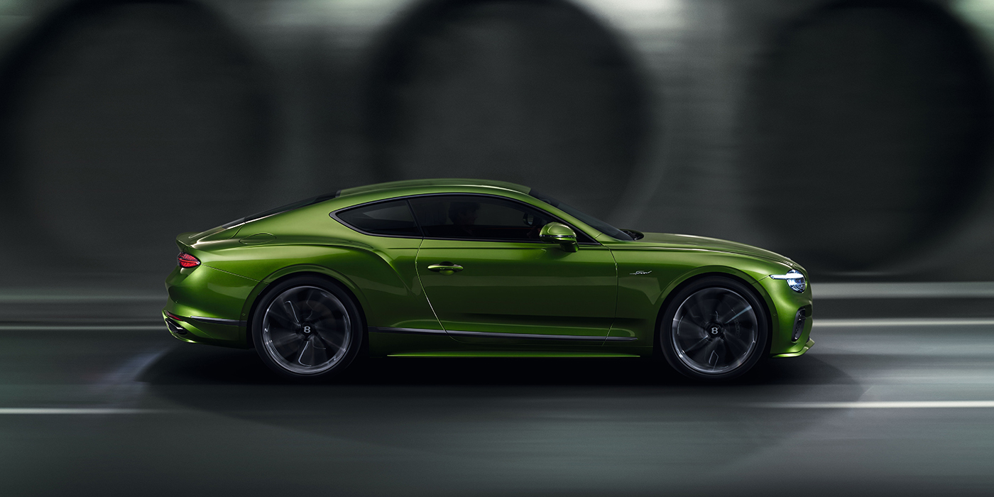 Bentley Hamburg Bentley Continental GT coupe in Tourmaline Green paint driving in profile on a dark road