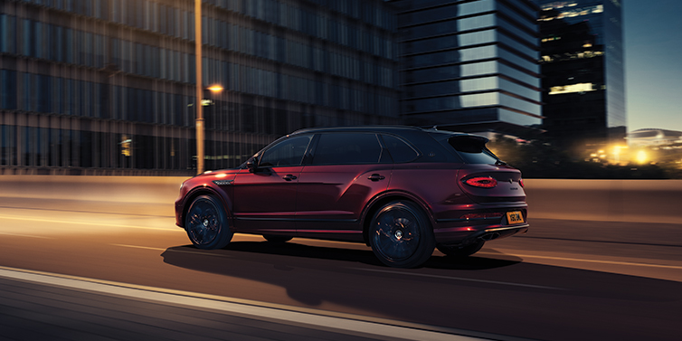 Bentley Hamburg Bentley Bentayga Extended Wheelbase Mulliner SUV in Cricket Ball red paint driving dynamically in city at night